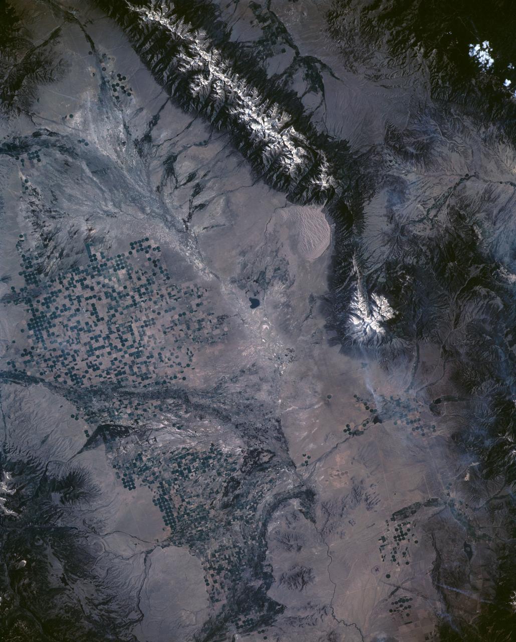 STS040-151-126 (5-14 June 1991) --- Croplands of the San Luis Valley stand out exceptionally clearly from low Earth orbit. The Rio Grande flows through the valley. Circular center pivot irrigation patterns have almost completely replaced the earlier rectangular grid pattern. Pinto beans are the specialty of the area. The Great Sand Dunes National Monument appears in fine detail near the center of the picture. The sands of these dunes have been blown from the valley floor by westerly winds in the course of the last few tens of thousands of years, now banked up against the foot of the Sangre de Christo Mountains (snowcapped peaks reach over 14000 feet). The town of Alamosa lies on the Rio Grande. The San Juan Mountains appear at the bottom left.