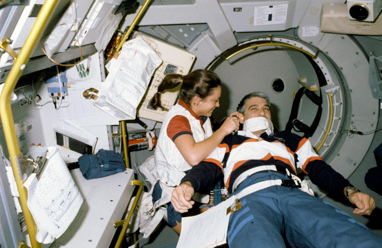 STS040-206-002 (5-14 June 1991)  --- Held in place by the Spacelab Life Sciences (SLS-1) Medical Restraint System (MRS), astronaut Sidney M. Gutierrez, pilot, gets his ears checked by astronaut Tamara E. Jernigan, mission specialist.  The two are in the SLS-1 module, onboard the Space Shuttle Columbia.  The scene was photographed with a 35mm camera.