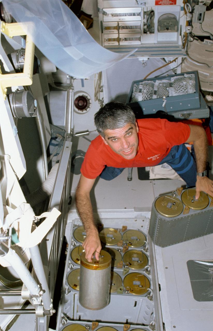 STS040-43-026 (5-14 June 1991) --- Astronaut Sidney M. Gutierrez, pilot, changes out the lithium hydroxide canisters on the Space Shuttle Columbia's middeck.  Gutierrez, making his first flight into space, was joined by six other crew members for the nine-day Spacelab Life Sciences (SLS-1) mission, devoted to life sciences research.  This middeck scene was photographed with a 35mm camera.