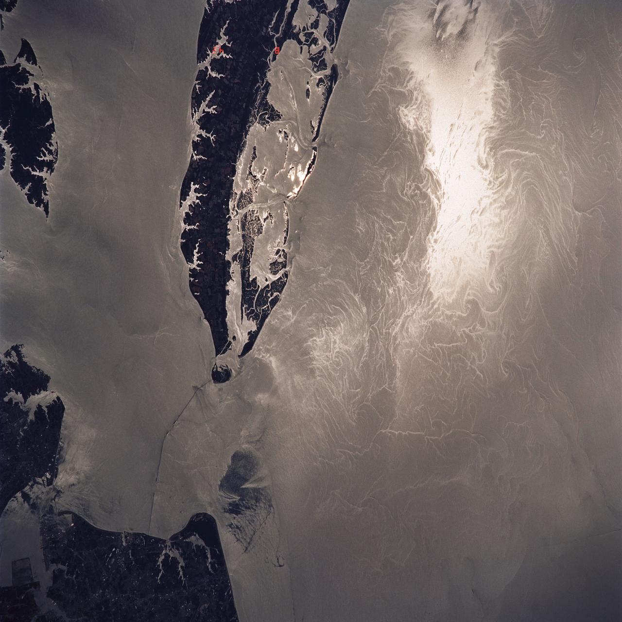 STS040-614-047 (5-14 June 1991) ---  This image is of the Norfolk, Virginia -- Southern Delmarva Peninsula Southern Chesapeake Bay Area as seen in sunlight.  The exposure is adjusted to emphasize the water patterns present.  The outgoing tide generates considerable turbulence as it passes through the mouth of the bay.  This is displayed by differences in reflective properties of the water surface due to differences in slope and turbidity.  Ship wakes and the wakes of subsurface structures are seen clearly.  The bridge tunnel system linking Norfolk with the peninsula and its effect on the system is quite apparent.  Sunglint images over land areas were also acquired which emphasize land-water boundaries as demonstrated here in the small Delmarva inlets as a tool for wetland mapping, and river, lake and even pond description.  During the first few days of the STS-40 mission the Eastern Seaboard of the United States was free of clouds and haze providing excellent photography of many of the major cities and the countryside of that area as well as the Gulf Stream.