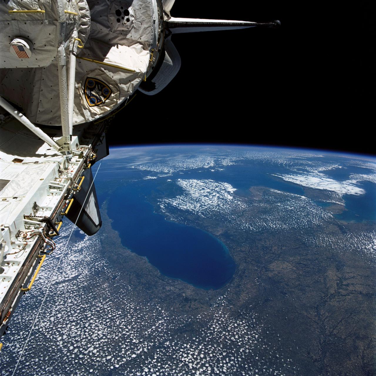 STS040-77-045 (6 June 1991) --- This image, photographed on June 6, 1991, is an oblique view looking north-northeast and shows most of the Great Lakes region.  Part of Columbia's cargo bay and the Spacelab Life Sciences (SLS-1) module are in the foreground.  In the center of the image is Lake Michigan with Chicago clearly visible along the southwest shore.  According to NASA photo experts studying the STS-40 imagery, this image shows several interesting meteorological phenomena.  The difference in temperature between the warming land and the cold lake waters is illustrated by the low level clouds.  The warming land surface results in rising air and the formation of clouds, while the lake waters are cold and result in the lakes remaining cloud free.  Also visible is evidence of lake breezes developing around several of the lakes.  This phenomena is also driven by the difference in temperature between the land and the water.  Winds blowing off the lakes must travel 25 - 30 miles inland before it warms sufficiently to create clouds.