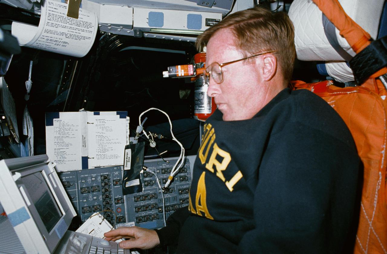 STS041-01-002 (6-10 Oct 1990) --- Astronaut Richard N. Richards, STS 41 mission commander, "borrows" the pilot's station to utilize a Shuttle portable onboard computer during the four-day flight.  The photo was made with a 35mm camera.