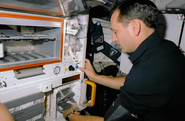 NASA image: STS-41 MS Akers rehydrates a grapefruit drink at OV-103's middeck galley