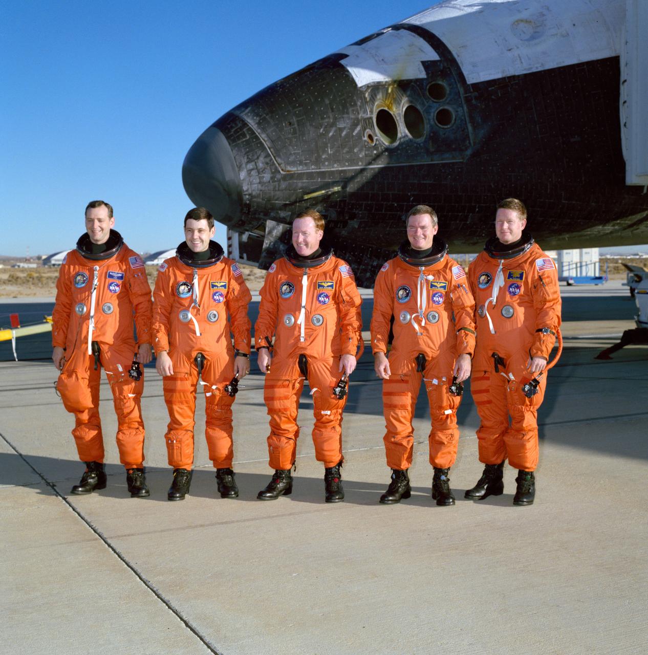 STS041-S-096 (10 Oct 1990) --- The five astronaut crewmembers of Discovery's most recent flight pose for their first photo back on terra firma following their successful four day mission in earth orbit. Discovery, partially visible in this frame, touched down at Edwards Air Force Base at 6:57 a.m. PDT, Oct. 10, 1990.  Astronaut Richard N. Richards (center) was mission commander.  He is flanked here by (left to right) Astronauts Thomas D. Akers, Robert D. Cabana, Bruce E. Melnick and William M. Shepherd.