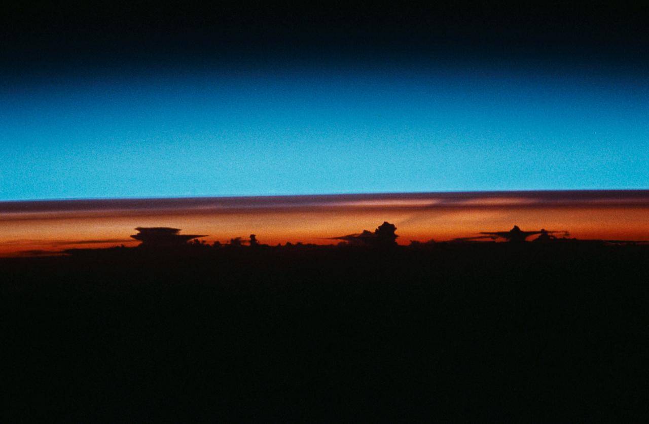 STS-43 Earth observation taken aboard Atlantis, Orbiter Vehicle (OV) 104, captures the Earth's limb at sunrise with unusual cloud patterns silhouetted by the sunlight and rising into the terminator lines.