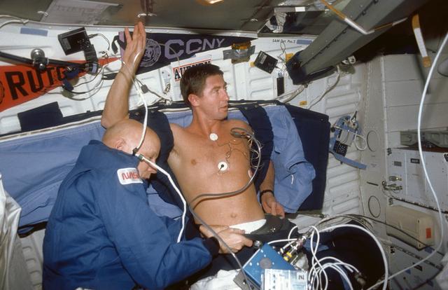 NASA image: STS-44 MS Musgrave assists Pilot Henricks with DSO 478 LBNP device on middeck