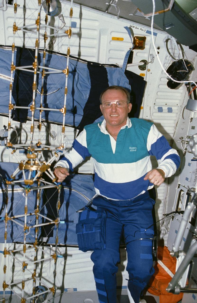STS048-10-023 (16 Sept 1991) --- Astronaut James F. Buchli poses with the structural test article (STA), a model of the space station truss structure.  The STA is part of the middeck zero gravity dynamics experiment (MODE).  MODE was designed to study the vibration characteristics of the jointed truss structure.  The structural test article includes four strain gauges and eleven accelerometers and is vibrated by an actuator.  Assembled by crewmembers in the Shuttle orbiter's middeck, the device is about 72 inches long with an 8-inch square cross section.