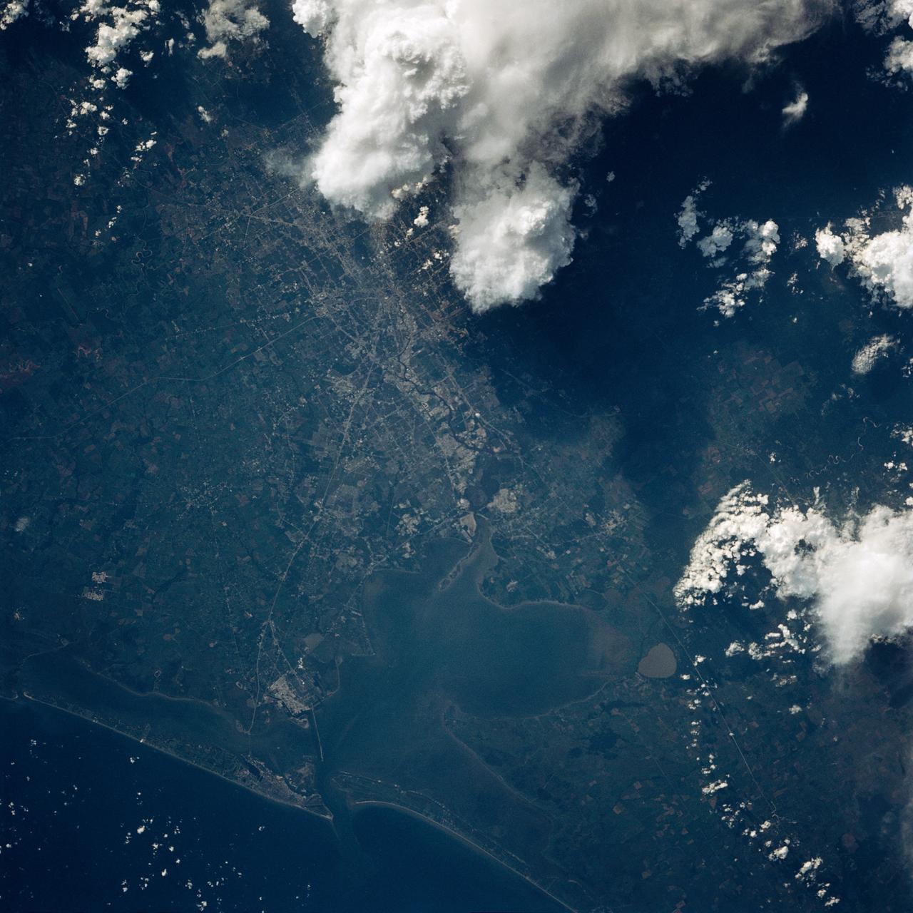 This color photo view of Houston (29.5N, 95.0W) was taken with a dual camera mount for comparitive film type testing. Compare this scene with STS048-106- 034 for an analysis of the unique properties of each type. Comparitive tests such as this aids in determining the kinds of information unique to each film system and evaluates and compares photography taken through hazy atmospheres. Color film is best at presenting the image as it appears to the human eye.