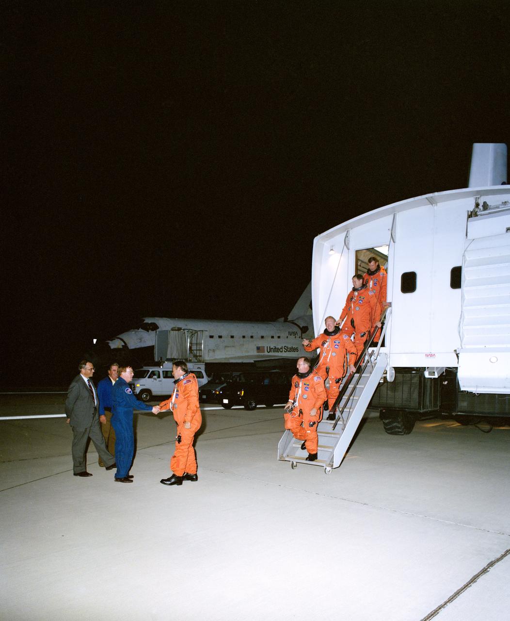 STS048-S-180 (18 Sept 1991) --- Having just completed a successful six day mission in Earth orbit, the five astronaut crewmembers for NASA's STS-48 spaceflight egress the crew transport vehicle (CTV).  Astronaut John O. Creighton shakes hands with astronaut Richard N. Richards, who had earlier flown a NASA aircraft for weather checkout in the landing area. Following the mission commander are astronauts James F. Buchli, Charles D. (Sam) Gemar, Kenneth S. Reightler and Mark N. Brown.  Discovery can be seen in the background.  The Edwards Air Force Base landing occurred at 12:38:38 a.m. (PDT), September 18, 1991.