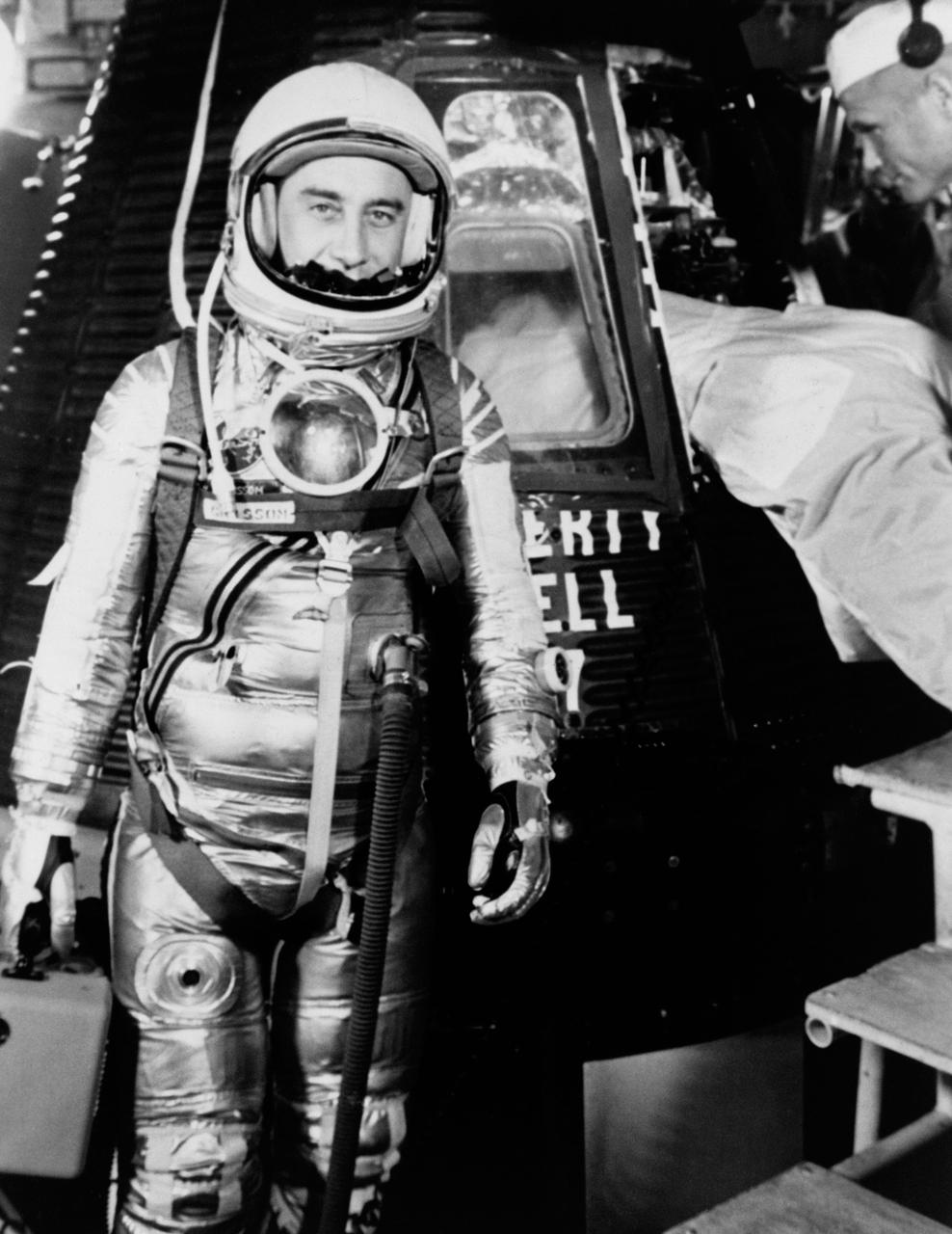 S61-02888 (1961) --- Astronaut Virgil I. (Gus) Grissom, suited up and ready to climb into Liberty Bell 7 spacecraft, stands in front of the capsule for a picture. Backup pilot John Glenn is in the right corner of the view behind Grissom. The Mercury-Redstone 4 (MR-4) mission was scrubbed a few hours later due to unfavorable weather over the launch pad. Photo credit: NASA