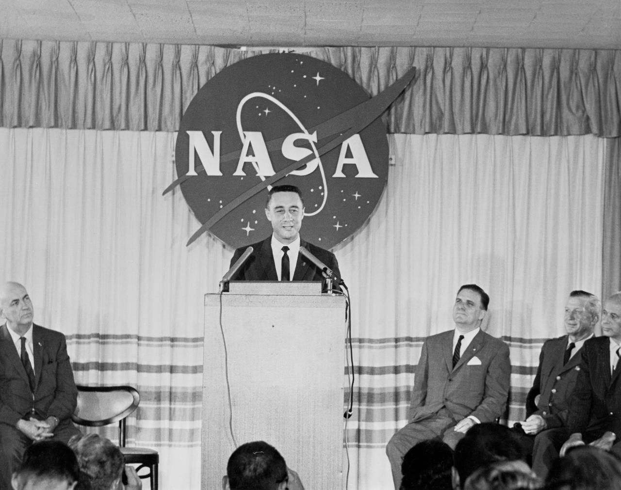S61-03676 (23 July 1961) --- Astronaut Virgil I. (Gus) Grissom speaks at a press conference on July 23, 1961 held at the Starlight motel. Behind him is a large representation of the NASA logo. Photo credit: NASA