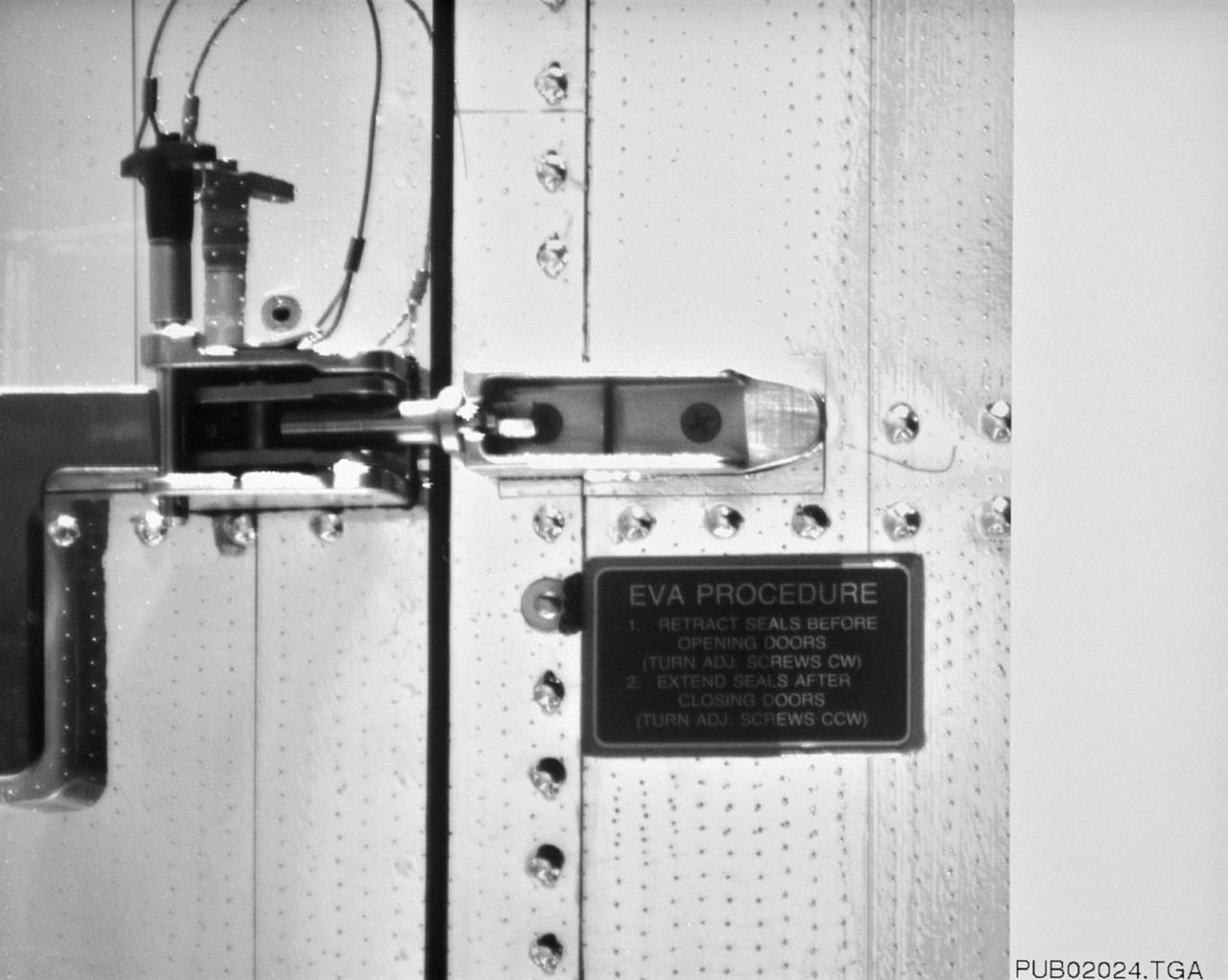 S61-E-010 (4 Dec 1993) --- This close-up view of a latch on the minus V3 aft shroud door of the Hubble Space Telescope (HST) was photographed with an Electronic Still Camera (ESC), and down linked to ground controllers soon afterward. Endeavour's crew captured the HST on December 4, 1993 in order to service the telescope over a period of five days. Four of the crew members will work in alternating pairs outside Endeavour's shirt sleeve environment to service the giant telescope. Electronic still photography is a relatively new technology which provides the means for a handheld camera to electronically capture and digitize an image with resolution approaching film quality. The electronic still camera has flown as an experiment on several other shuttle missions.
