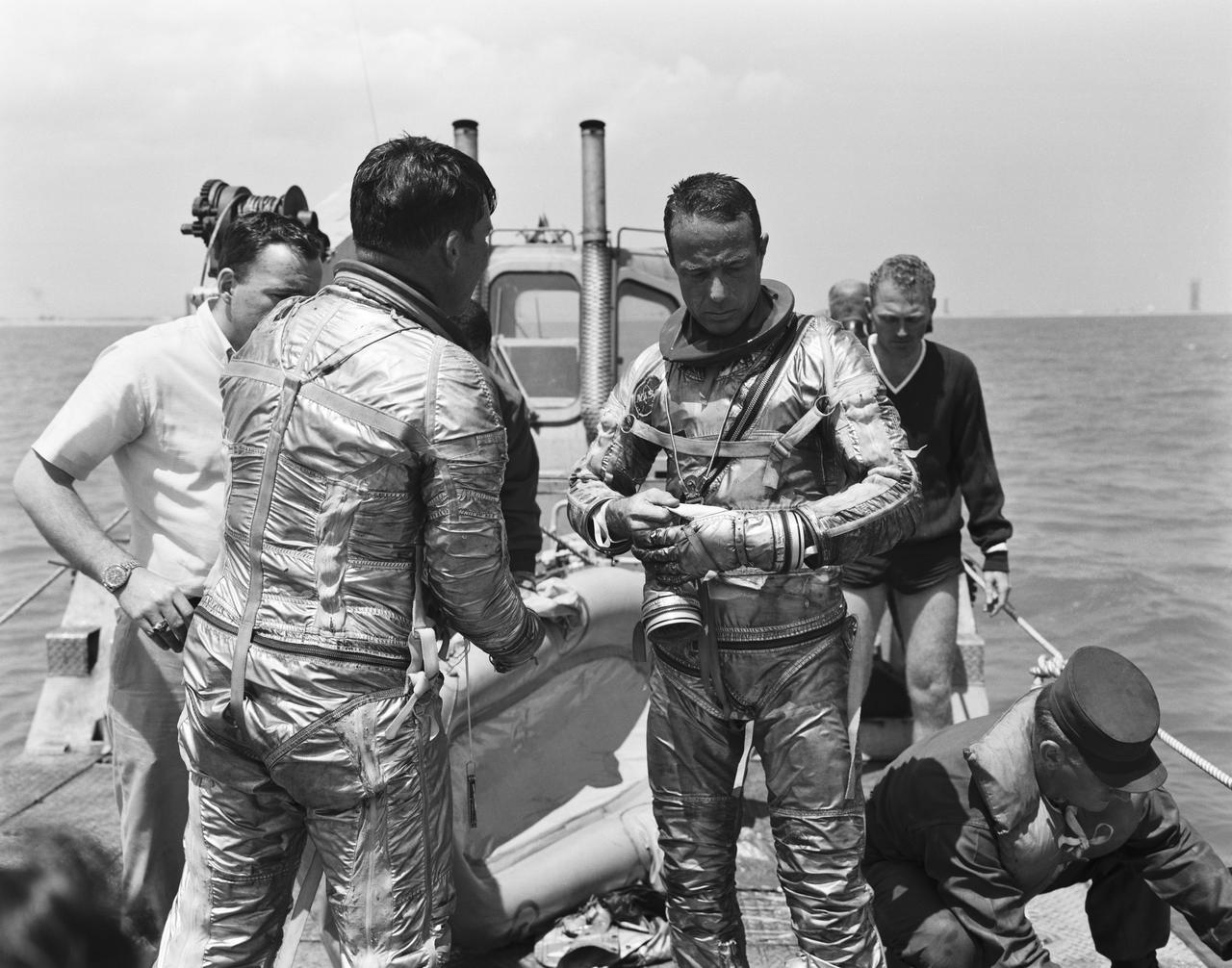 S62-01355 (1962) --- Project Mercury astronauts M. Scott Carpenter, prime pilot of the Mercury-Atlas 7 (MA-7) spaceflight, prepares to go through a water egress test. Astronaut Walter M. Schirra (back to camera), the backup MA-7 pilot is also present. Carpenter and Schirra are in the Mercury pressure suit, without the helmet. Behind them is an inflated life raft. Photo credit: NASA