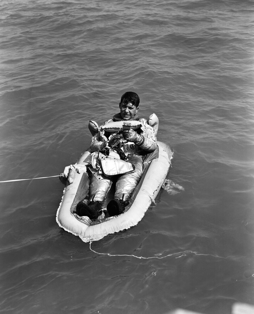 S62-01379 (1962) --- Astronaut Walter M. Schirra Jr., wearing his pressure suit, is seated in a life raft during a portion of his water egress training. Photo credit: NASA