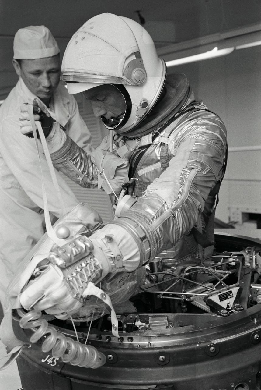 S62-01383 (1962) --- Project Mercury astronaut M. Scott Carpenter, prime pilot of the Mercury-Atlas 7 (the nation's second manned orbital flight), completes top egress training in the white room at Cape Canaveral, Florida. The line he is holding is known as the "man line" which attaches the survival kit to the astronaut. The bag is the survival kit he carries for contingency landings. Clearly visible around his neck is the bag containing the life vest. Photo credit: NASA