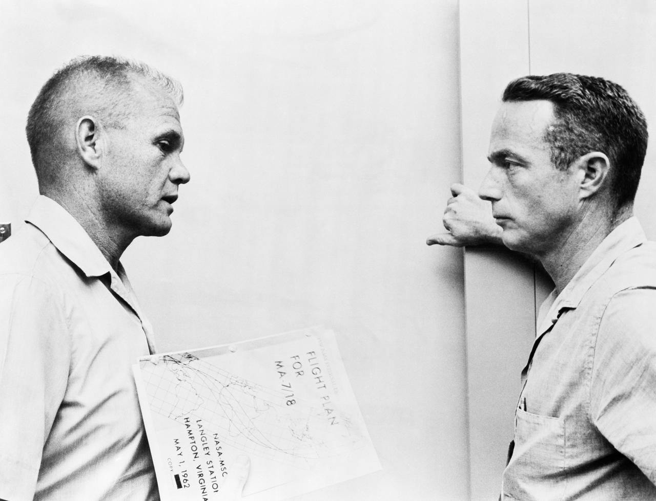 S62-02830 (1962) --- Astronauts John Glenn (left) and Scott Carpenter go over the flight plan for MA-7 mission. (62-MA7-63) Photo credit: NASA