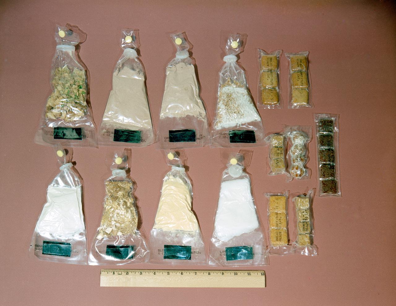S62-08743 (1962) --- Food kit used by Mercury astronauts. Some is dehydrated and needs water, other packets are ready to eat. Size is measured relative to a ruler. Included are packets of mushroom soup, orange-grapefruit juice, cocoa beverage, pineapple juice, chicken with gravy, pears, strawberries, beef and vegetables and other assorted food containers. Photo credit: NASA