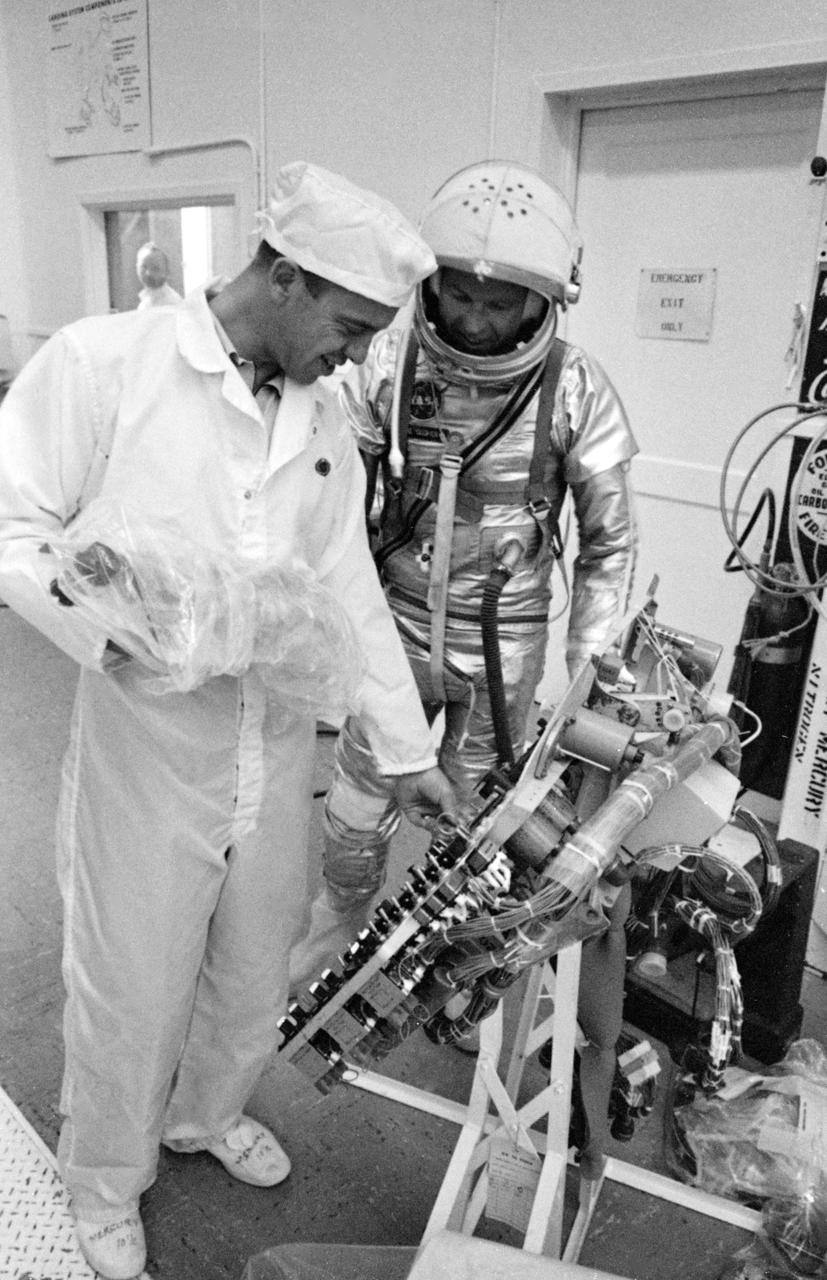 S63-03965 (1963) --- Astronauts Alan Shepard (left) and L. Gordon Cooper Jr.(in suit) check over the instrument panel from Mercury spacecraft #20. It contains the instruments necessary to monitor spacecraft systems and sequencing, the controls required to initiate primary sequences manually, and the necessary flight control displays. Photo credit: NASA
