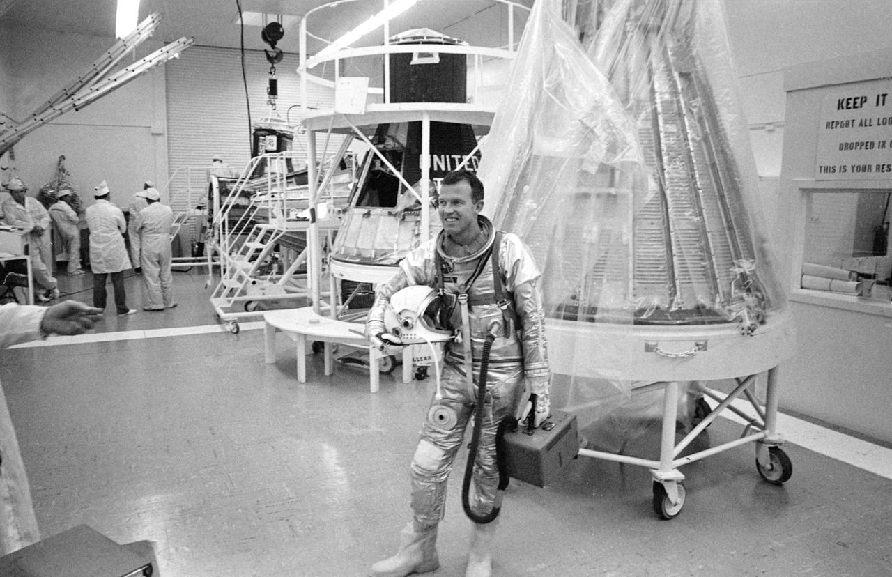 S63-03966 (1963) --- Astronaut L. Gordon Cooper Jr., prime pilot for the Mercury-Atlas 9 (MA-9) mission, carrying the portable air conditioner to his spacesuit, leaves Hangar S after completing the day's simulated flight tests. Photo credit: NASA
