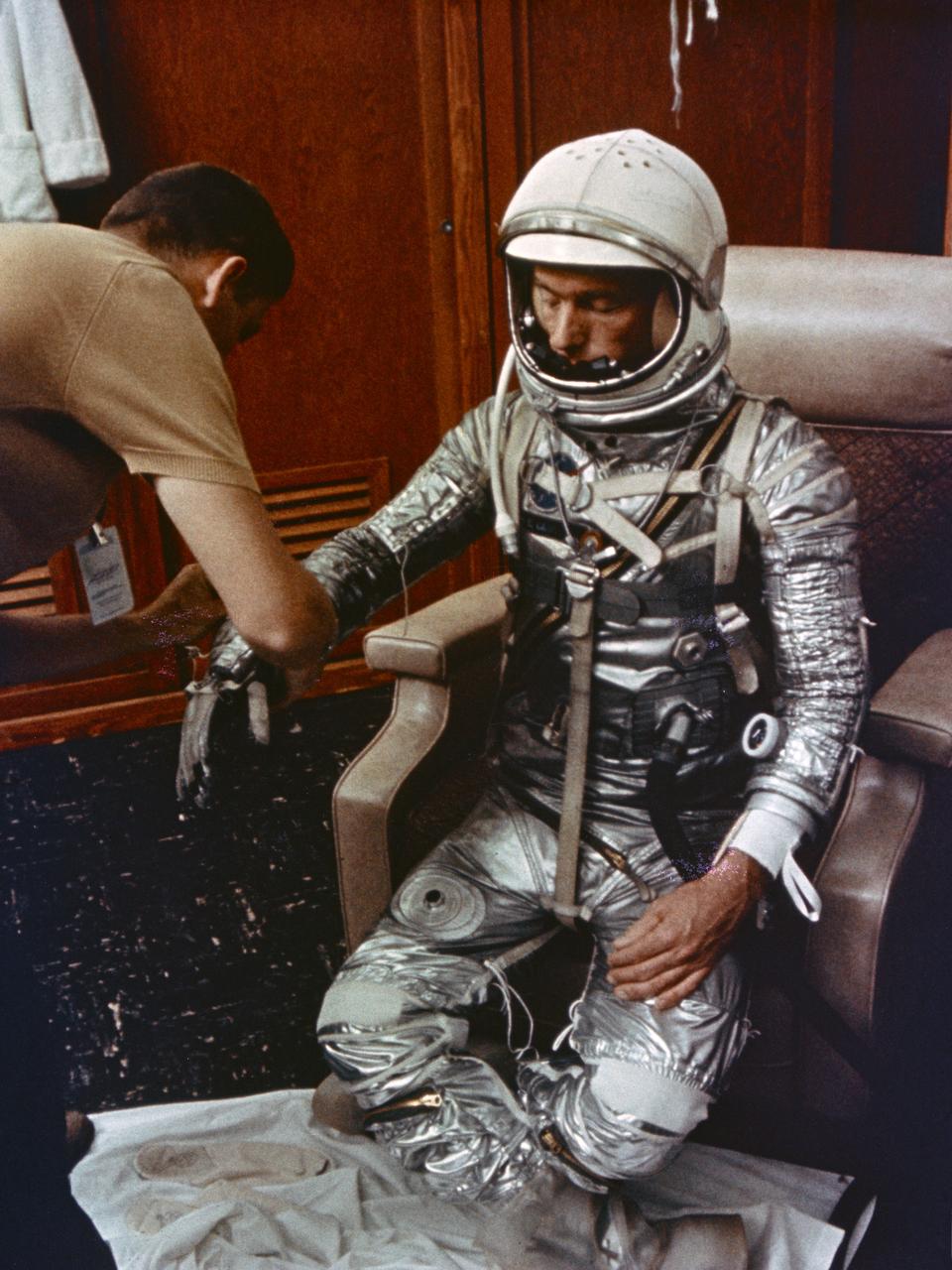 S64-14870 (May 1962) --- Astronaut M. Scott Carpenter, prime pilot for the Mercury-Atlas 7 (MA-7) flight, is seen in Hangar S crew quarters during a preflight suiting activity at Cape Canaveral, Florida. He is assisted in suiting by technician Al Rochford. In this view, Carpenter is fully suited and is having his gloves adjusted. Photo credit: NASA