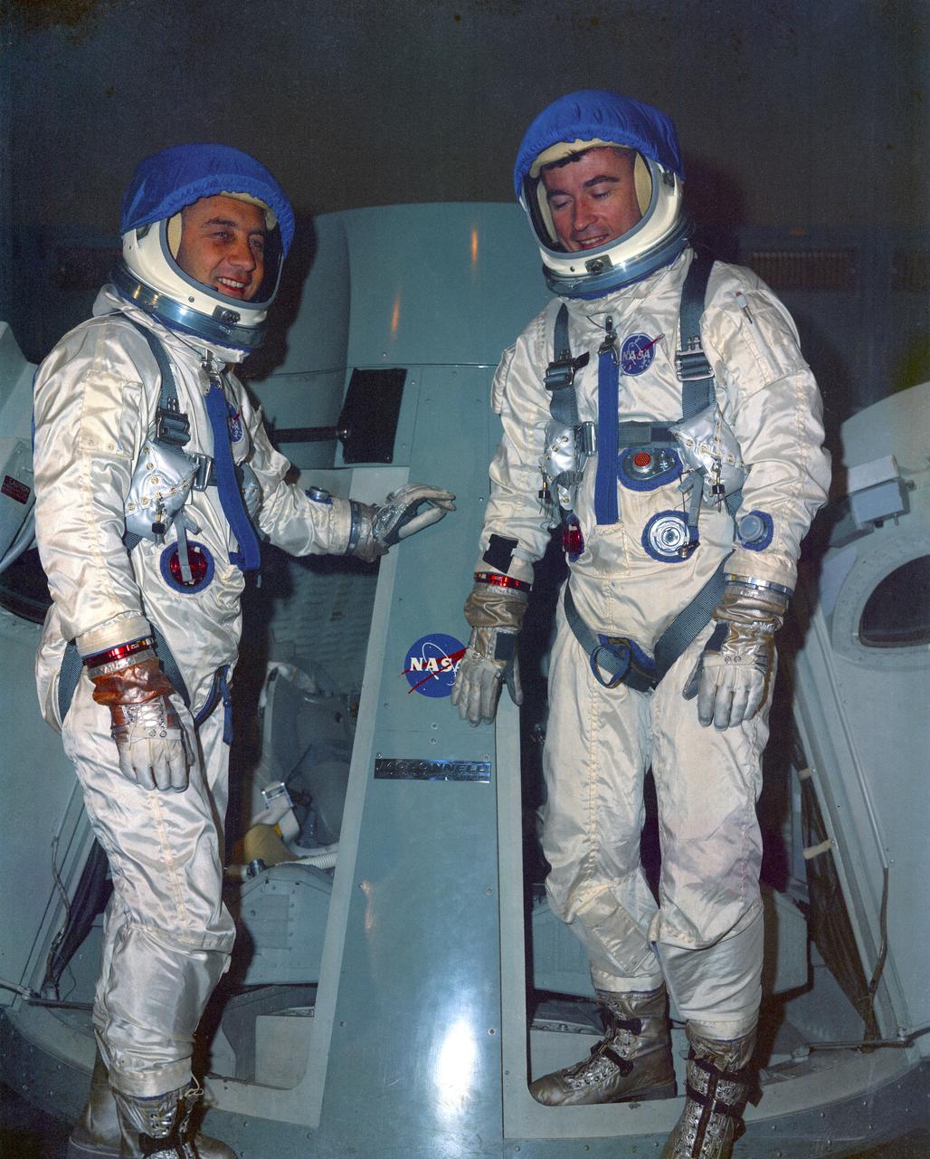 Seen in this view left to right Astronauts Virgil I. Grissom and John Young stand in front of Gemini trainer prior to test, MCC.        MSC, HOUSTON, TX  CN