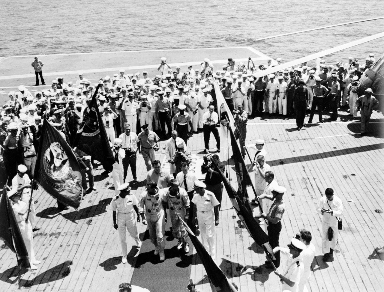 S65-19530 (7 June 1965) --- The red carpet treatment is given to the Gemini-Titan 4 astronauts Edward H. White II and James A. McDivitt as they arrive on the flight deck of the aircraft carrier USS Wasp after their record breaking 62-revolution, 97-hour and 56-minute flight which ended in the Atlantic Ocean about 400 miles east of Cape Kennedy at 12:12 p.m. (EST) on June 7, 1965. Here they are shown being welcomed by members of the crew and NASA people. White and McDivitt (center) walk on the red carpet flanked by Capt. J.W. Conger (left), commander of the ship; and Rear Adm. W.M. McCormick, commander, Carrier Division 14, Atlantic Fleet. NASA's Gemini-4 flight landed about 48 miles short of the aircraft carrier.