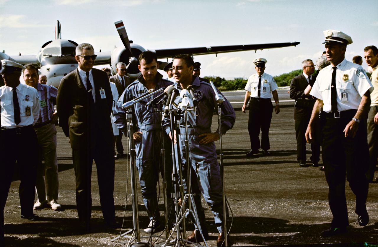 S65-20422 (24 March 1965) --- Astronauts John W. Young (left), pilot; and Virgil I. Grissom, command pilot, stand at microphones at the Cape's skid strip after being flown in from the recovery ship, USS Intrepid. The two astronauts made three orbits of Earth during the first manned Gemini flight the day before.