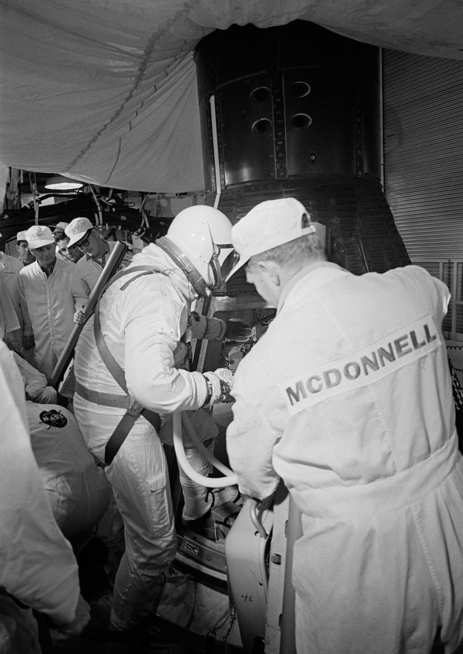 S65-20604 (23 March 1965) --- Astronaut John W. Young, the pilot of the Gemini-Titan 3 three-orbit mission, is assisted by a McDonnell Aircraft Corp. engineer as he enters the Gemini spacecraft in the white room atop the Gemini launch vehicle.