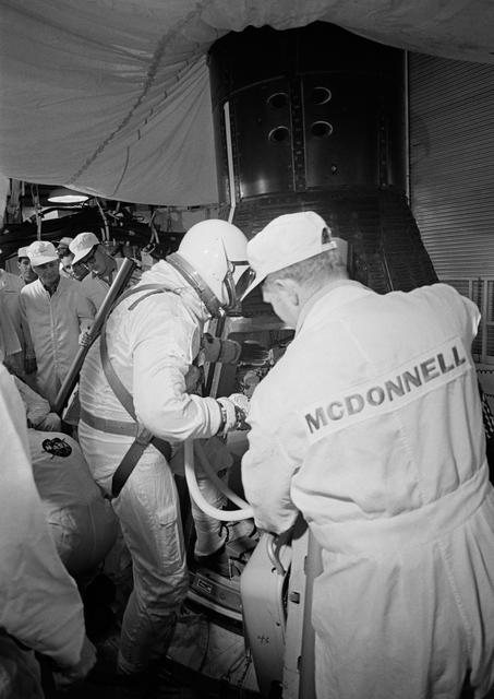NASA image: Astronaut John Young assisted into Gemini spacecraft in white room