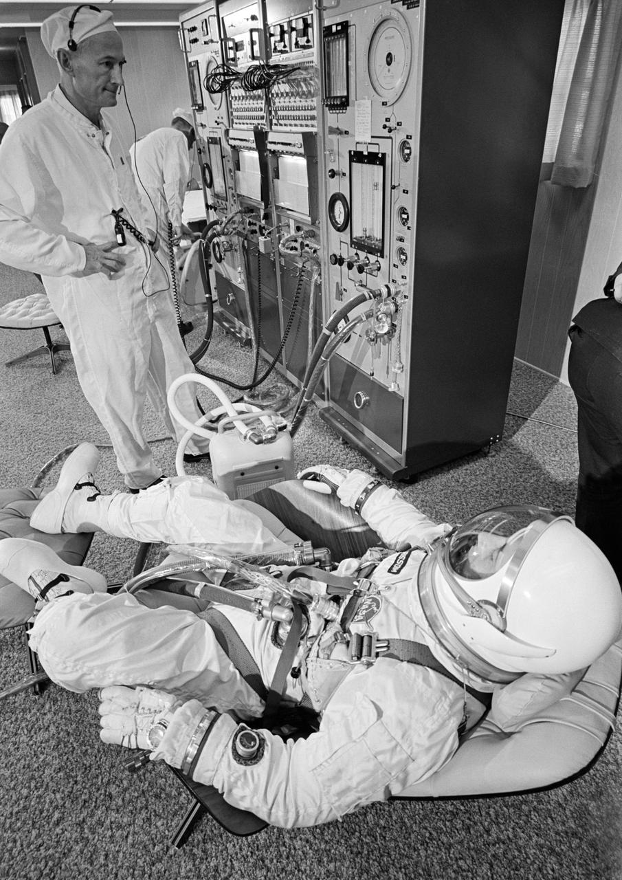 S65-20639 (18 March 1965) --- Astronaut Virgil I. Grissom, Gemini-Titan 3 command pilot, reclines on a couch in the Pad 16 ready room during preflight checks prior to going to Pad 19 for flight simulations in the Gemini-3 spacecraft. Joe Schmitt, suit technician from NASA?s Manned Spacecraft Center Crew Systems Division, stands by to assist Grissom.