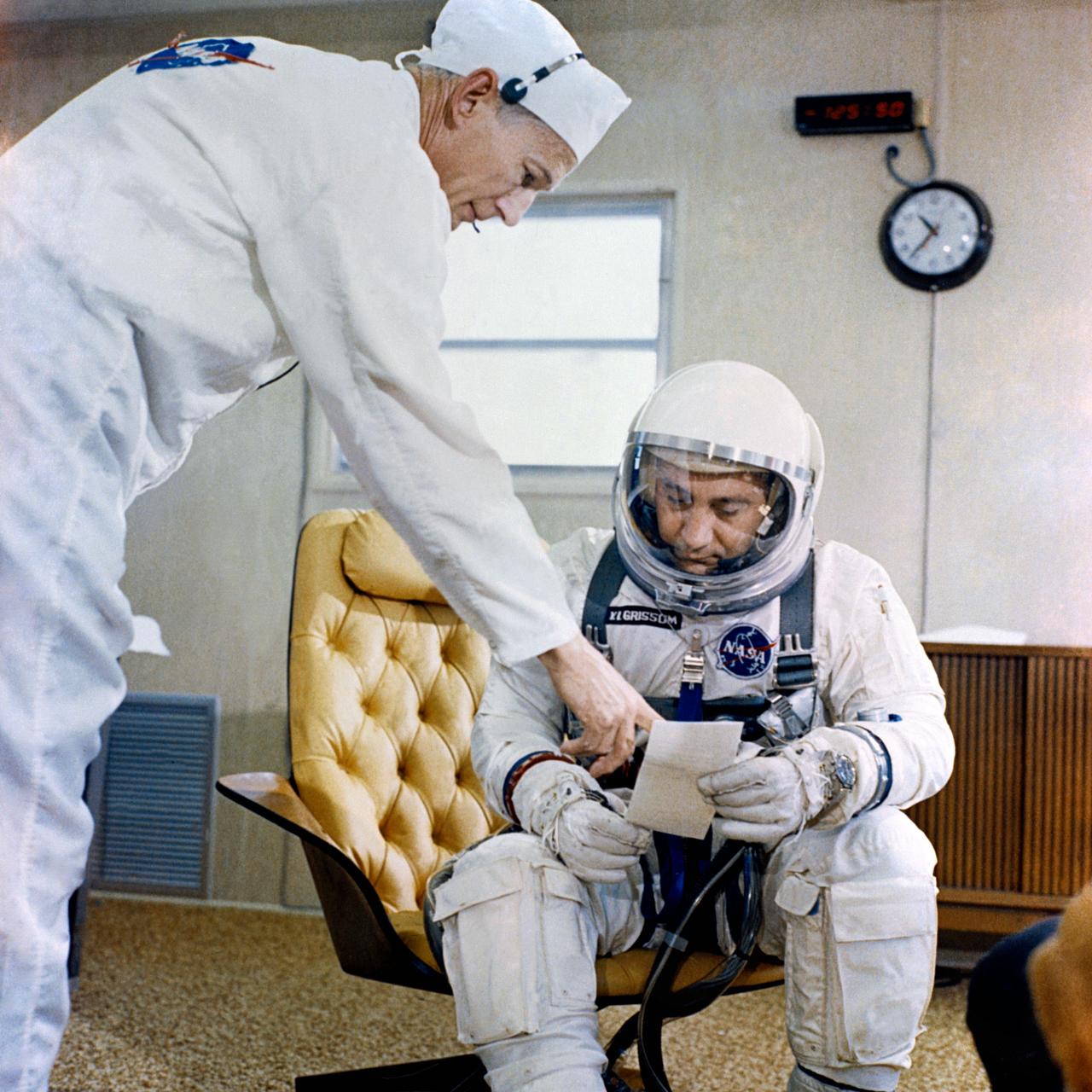 S65-23486 (23 March 1965) --- Astronaut Virgil I. Grissom, command pilot of the Gemini-Titan 3 space flight, is shown in the suiting trailer at Pad 16 going over a checklist with suit technician Joe Schmitt.