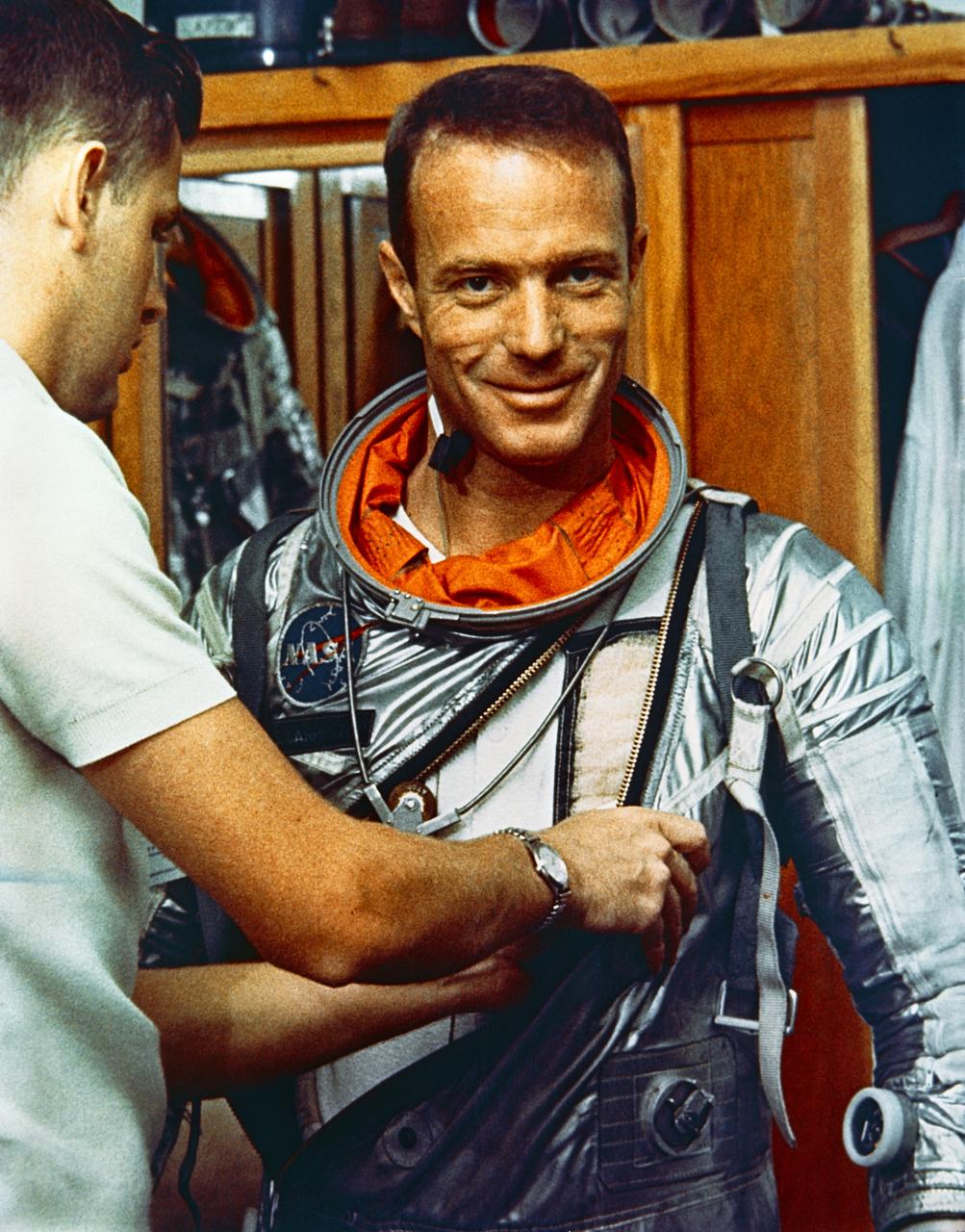 S65-24624 (22 May 1962) --- Astronaut M. Scott Carpenter, prime pilot for the Mercury-Atlas 7 (MA-7) flight, is seen in Hangar S crew quarters during a suiting exercise. He smiles at camera as suiting technician Al Rochford adjusts his suit. Photo credit: NASA