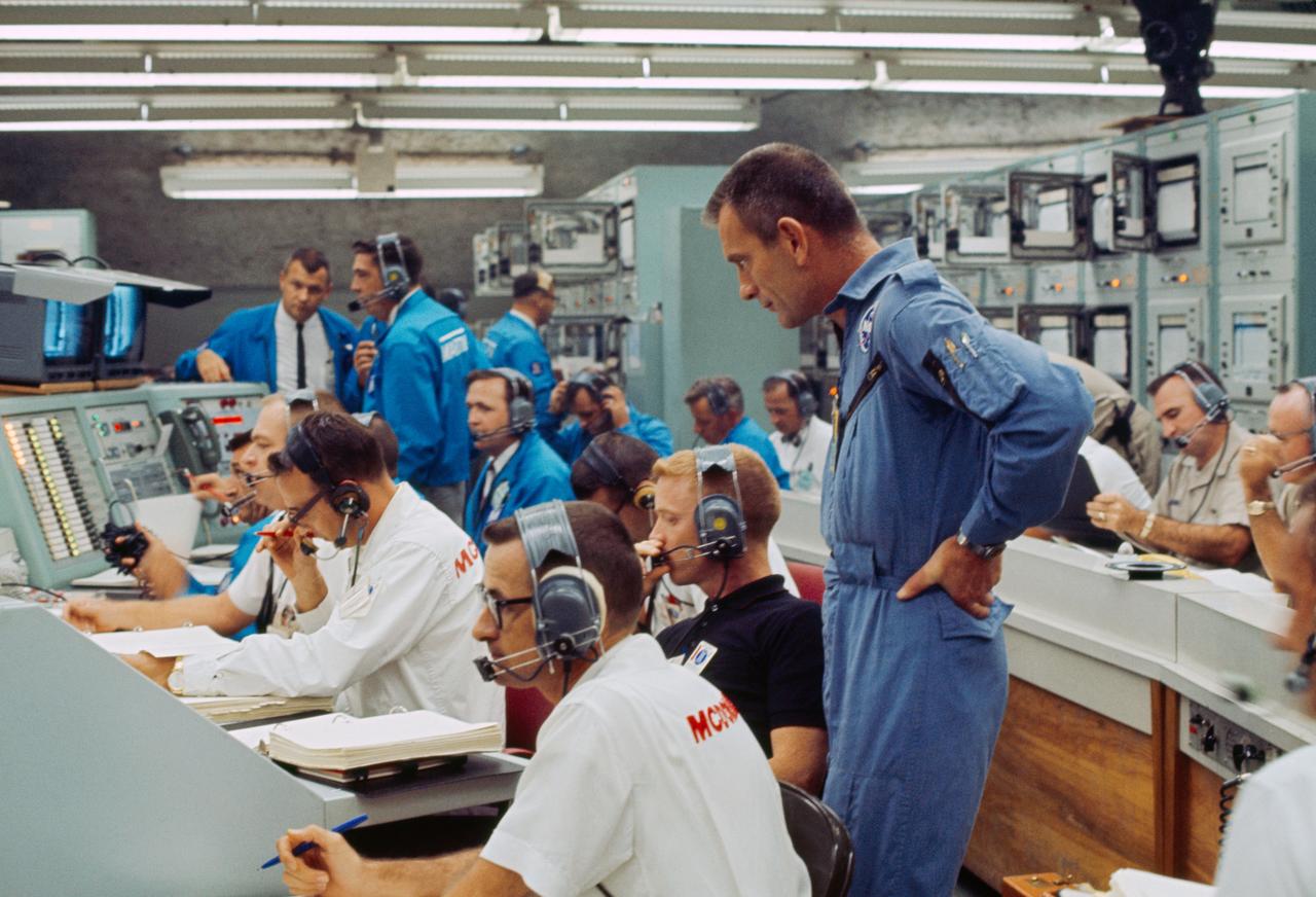 S65-28742 (21 Aug. 1965) --- View of Mission Control Center at Cape Kennedy, Florida, moments after the Gemini-5 spacecraft was launched from Pad 19 on Aug. 21, 1965. Standing at right is astronaut Donald K. Slayton, assistant director for Flight Crew Operations, Manned Spacecraft Center. Seated (wearing dark shirt) is astronaut Russell L. Schweickart. Other NASA and McDonnell Aircraft Col. personnel also monitor the progress of the flight.