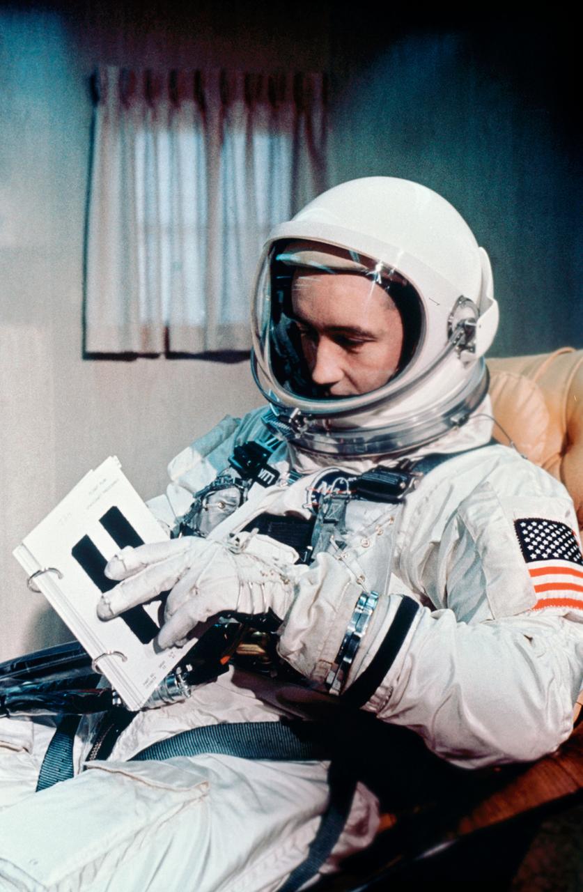 S65-29643 (3 June 1965) --- Astronaut James A. McDivitt, Gemini-4 command pilot, is shown in full spacesuit in the suit trailer prior to launch. He is reviewing a crew procedures flip book.