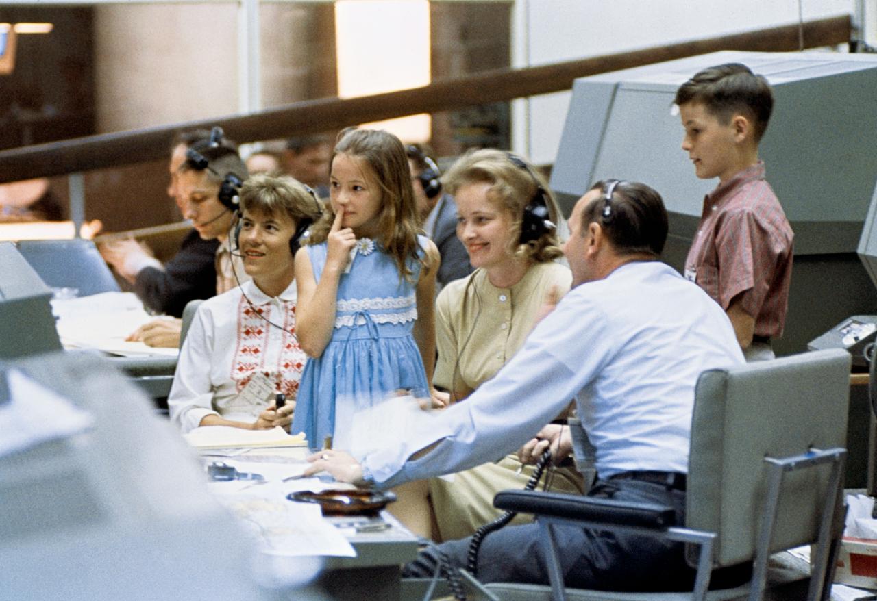 S65-30411 (9 June 1965) --- The families of Gemini 4 astronauts James A. McDivitt and Edward H. White II visited the Mission Control Center in Houston. In the foreground, left to right, are Mrs. Patricia McDivitt, daughter Bonnie White, Mrs. Patricia White, flight director Christopher C. Kraft Jr., and Edward White III. Each of the family members talked with the astronauts as they passed over the United States. Photo credit: NASA