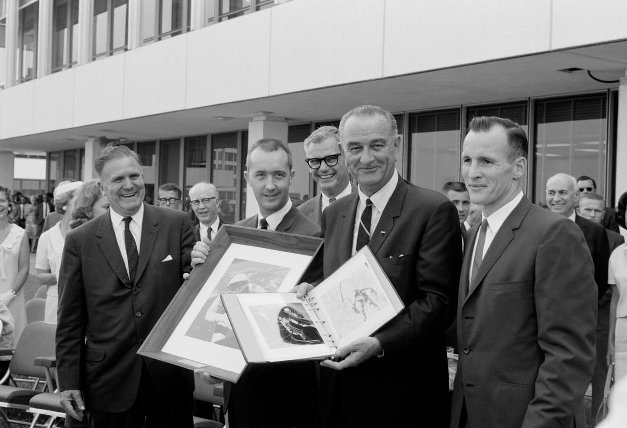 S65-33250 (11 June 1965) --- President Lyndon B. Johnson holds a Gemini-4 souvenir photo album which he was presented during his visit to the space center. Left to right, are James E. Webb, NASA administrator, Washington, D.C.; astronaut James A. McDivitt, command pilot of the Gemini-4 spaceflight; Dr. Robert C. Seamans Jr., NASA associate adminitrator; the President; and astronaut Edward H. White II, pilot of the Gemini-4 mission. McDivitt holds a framed picture of White's "spacewalk" which was also given the President.
