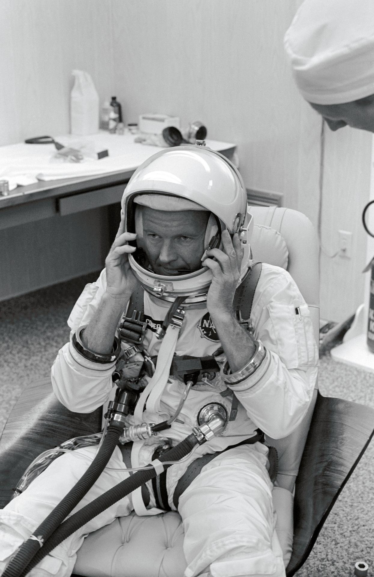 Gordon Cooper adjusts his helmet during a suiting up exercise