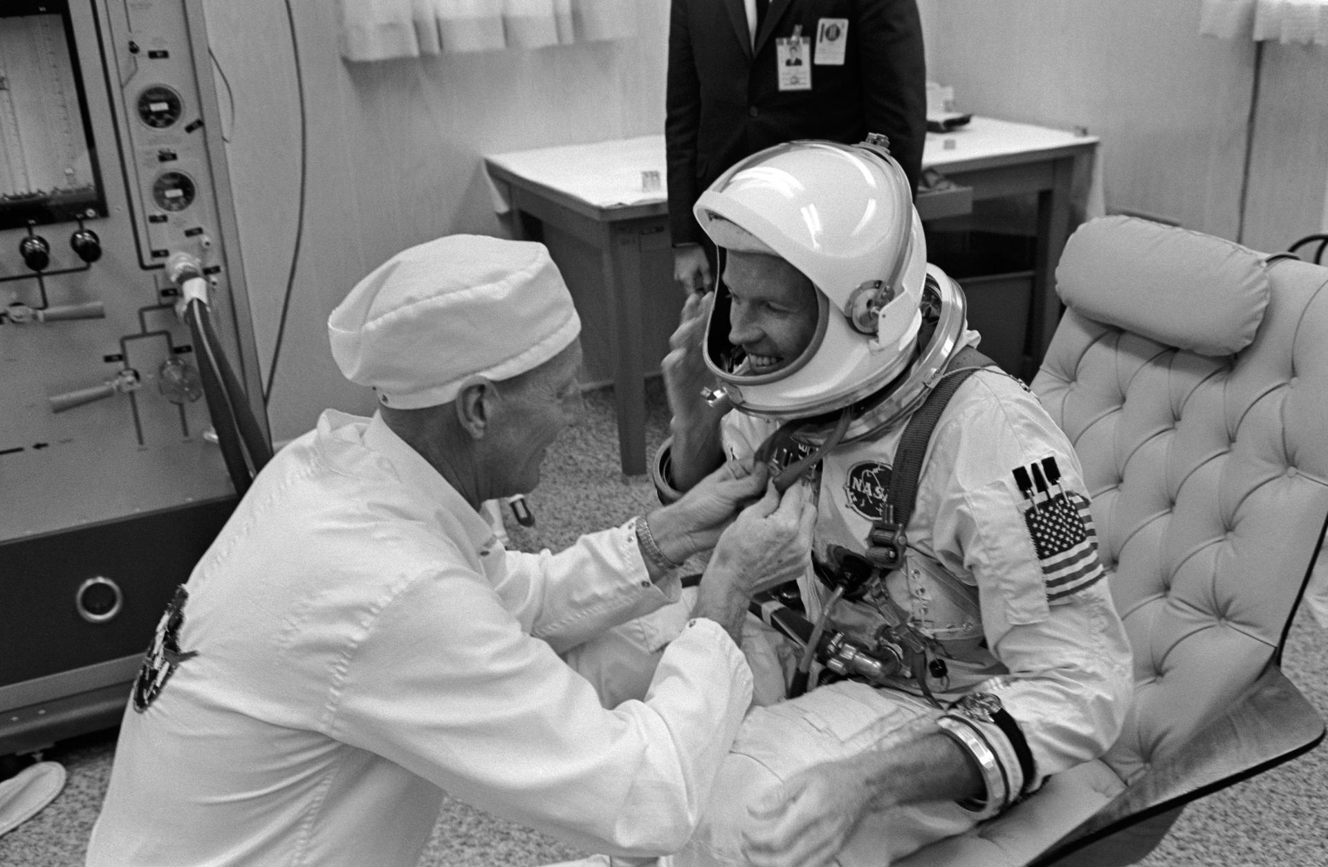 Gordon Cooper is assisted with his space suit