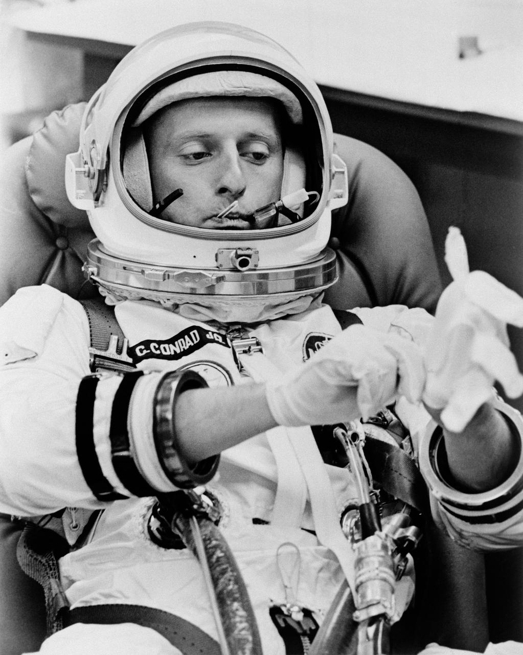 S65-46377 (21 Aug. 1965) --- Astronaut Charles Conrad Jr. pulls on a pair of white undergloves and has his temperature taken during suiting up operations on the morning of liftoff of Gemini-5 spaceflight from Cape Kennedy, Florida.