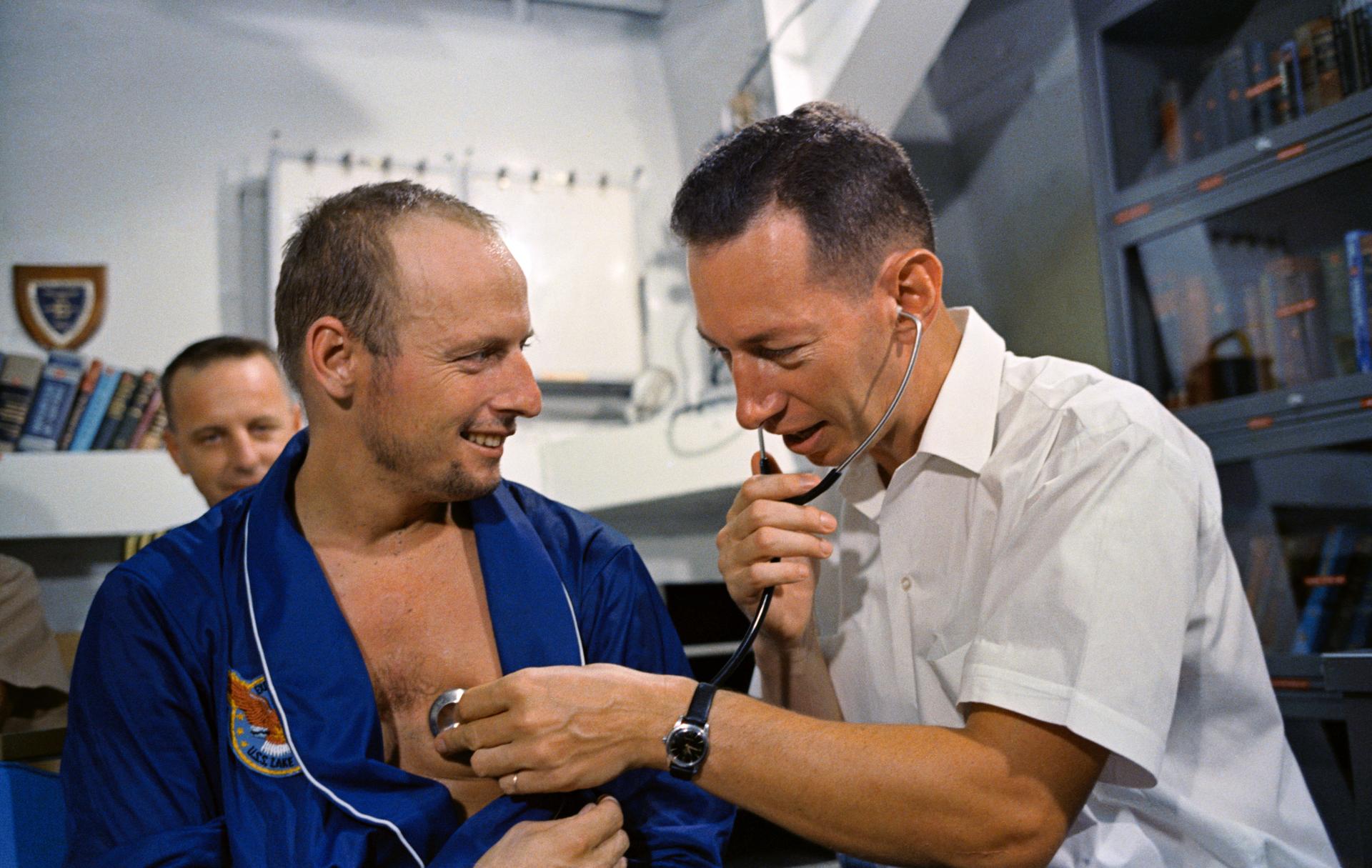 Pete Conrad has his heart checked by a doctor with a stethoscope.