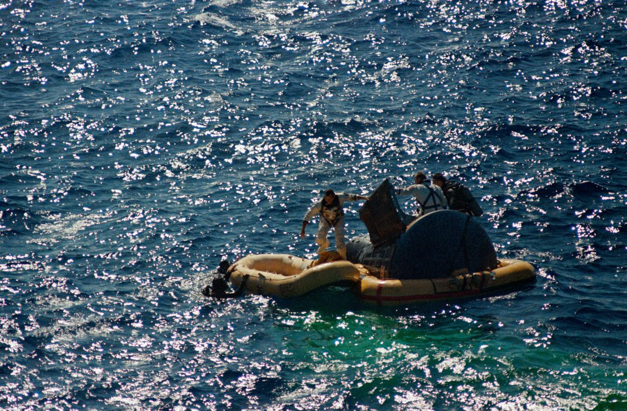 S65-51653 (29 Aug. 1965) --- Astronauts L. Gordon Cooper Jr. and Charles Conrad Jr. exit their spacecraft after splashdown of the Gemini-5 spacecraft. They are photographed boarding a life raft with the help of Navy divers.