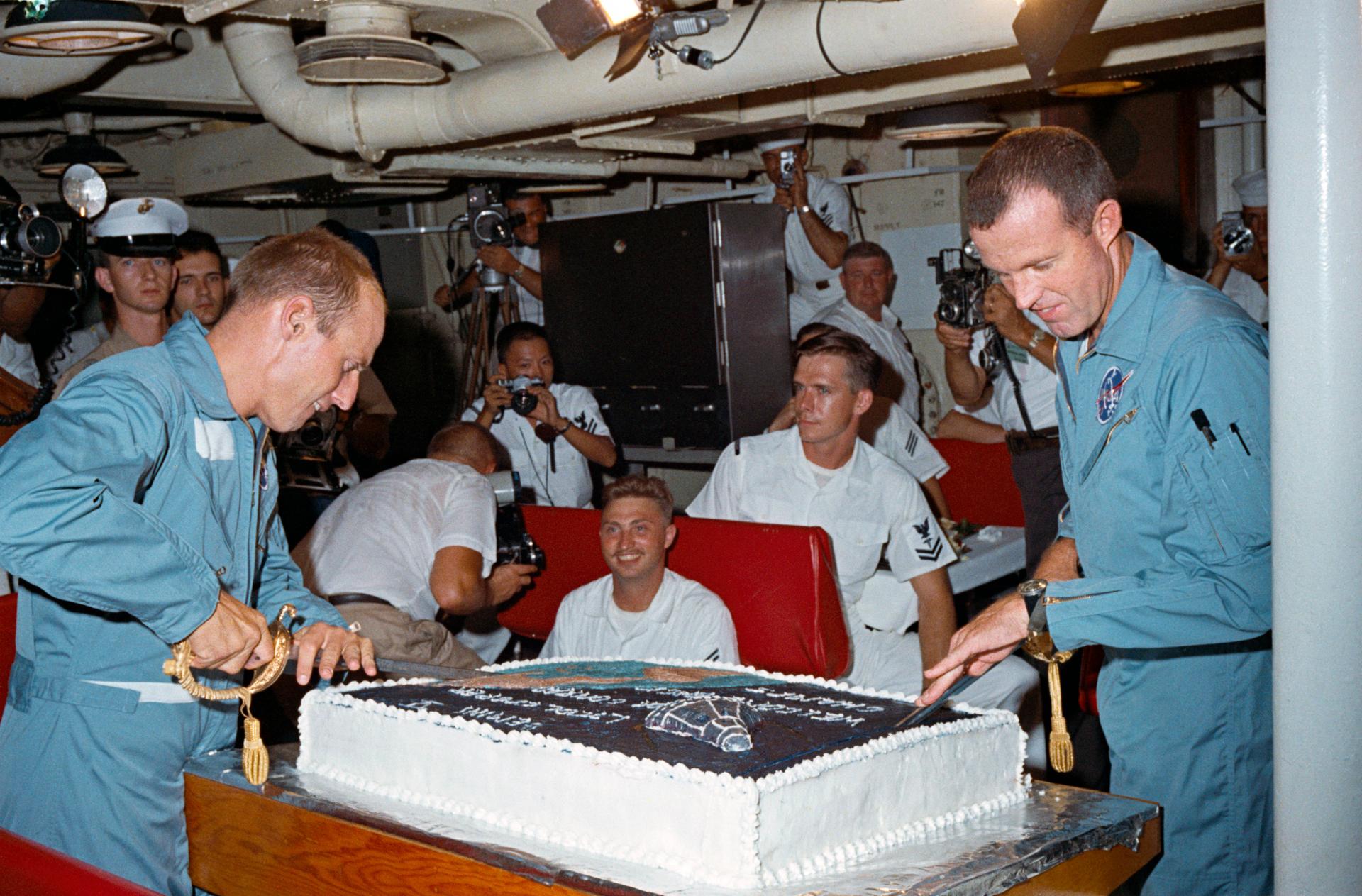 The crew of Gemini 5 slice a big cake after their successful flight