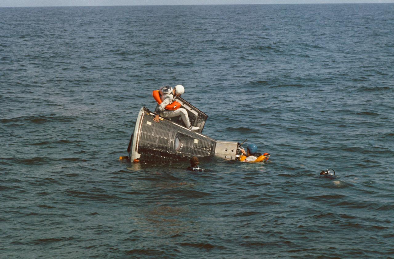 S65-55562 (15 Oct. 1965) --- Astronaut James A. Lovell Jr., prime crew pilot for the Gemini-7 spaceflight, sits on top of the Gemini spacecraft Static Test Article during water egress training in the Gulf of Mexico. Astronaut Frank Borman (wearing blue helmet), prime crew command pilot, hangs onto the nose of the spacecraft. NASA divers are in the water as a safety precaution. Photo credit: NASA