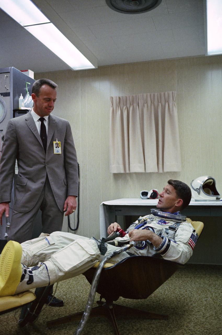 S65-59975 (15 Dec. 1965) --- Astronaut Walter M. Schirra Jr. (seated), command pilot of NASA's Gemini-6 spaceflight, relaxes in the suiting trailer at Launch Complex 16 during the Gemini-6 prelaunch countdown at Cape Kennedy, Florida. He is talking with astronaut Alan B. Shepard Jr., chief, Astronaut Office, Manned Spacecraft Center. Photo credit: NASA or National Aeronautics and Space Administration