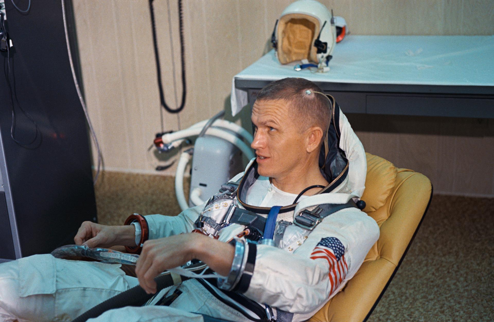 Frank Borman sits in his space suit on a padded recliner before launch