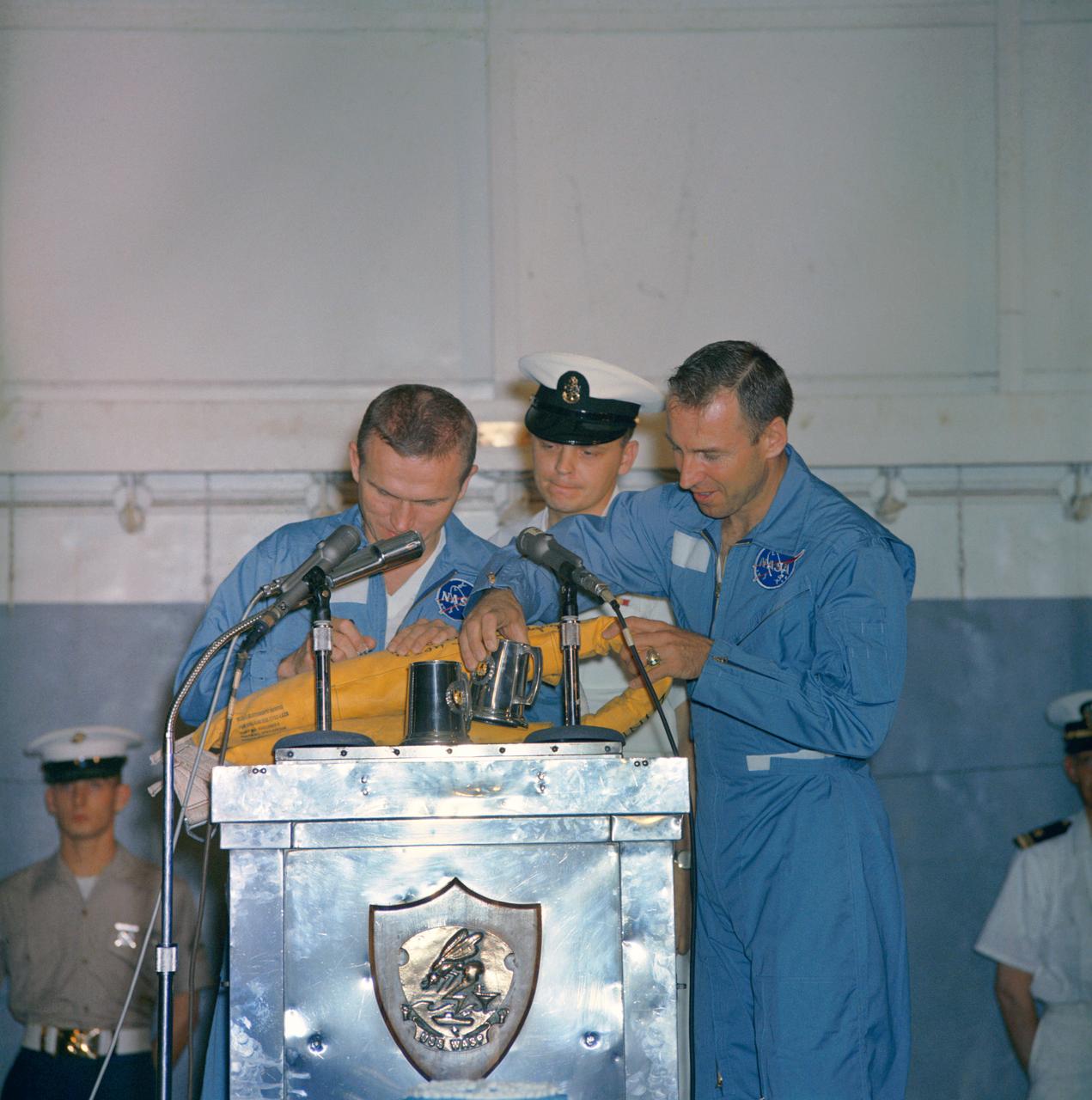S65-61834 (18 Dec. 1965) --- Astronauts Frank Borman (left), Gemini-7 command pilot, and James A. Lovell Jr., pilot, take time out during their welcoming ceremonies aboard the aircraft carrier USS Wasp to autograph a life preserver. The National Aeronautics and Space Administration's Gemini-7 spacecraft splashed down in the western Atlantic recovery area at 9:05 a.m. (EST), Dec. 18, 1965, to conclude a highly successful 14-day mission in space. Photo credit: NASA