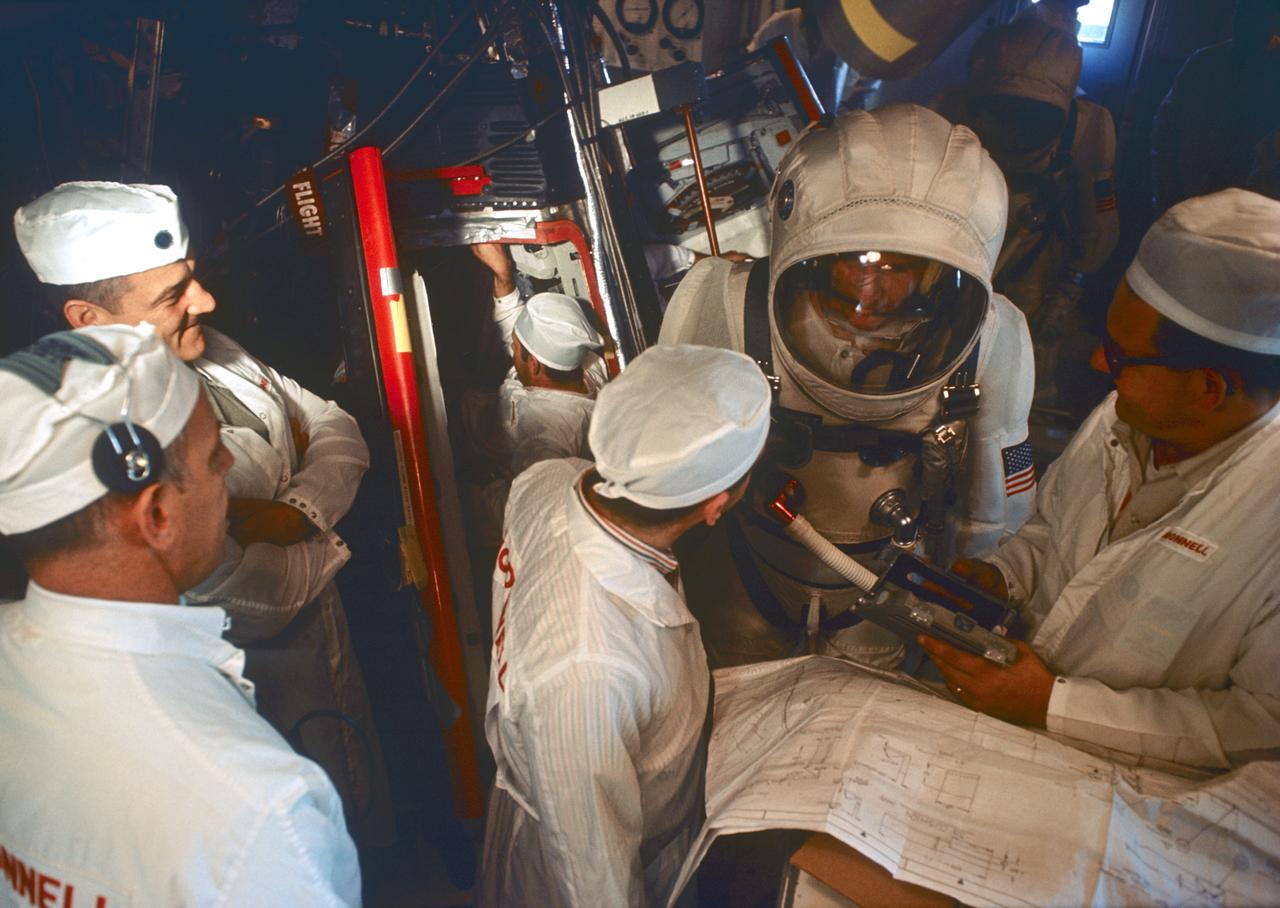 S65-61837 (27 Nov. 1965) --- The Gemini-7 backup crew seen in the White Room atop Pad 19 during Gemini-7 simulation flight activity. McDonnell Aircraft Corporation technicians assist in the exercise. Astronaut Edward H. White II (in foreground) is the Gemini-7 backup crew command pilot; and astronaut Michael Collins (right background) is the backup crew pilot. Photo credit: NASA