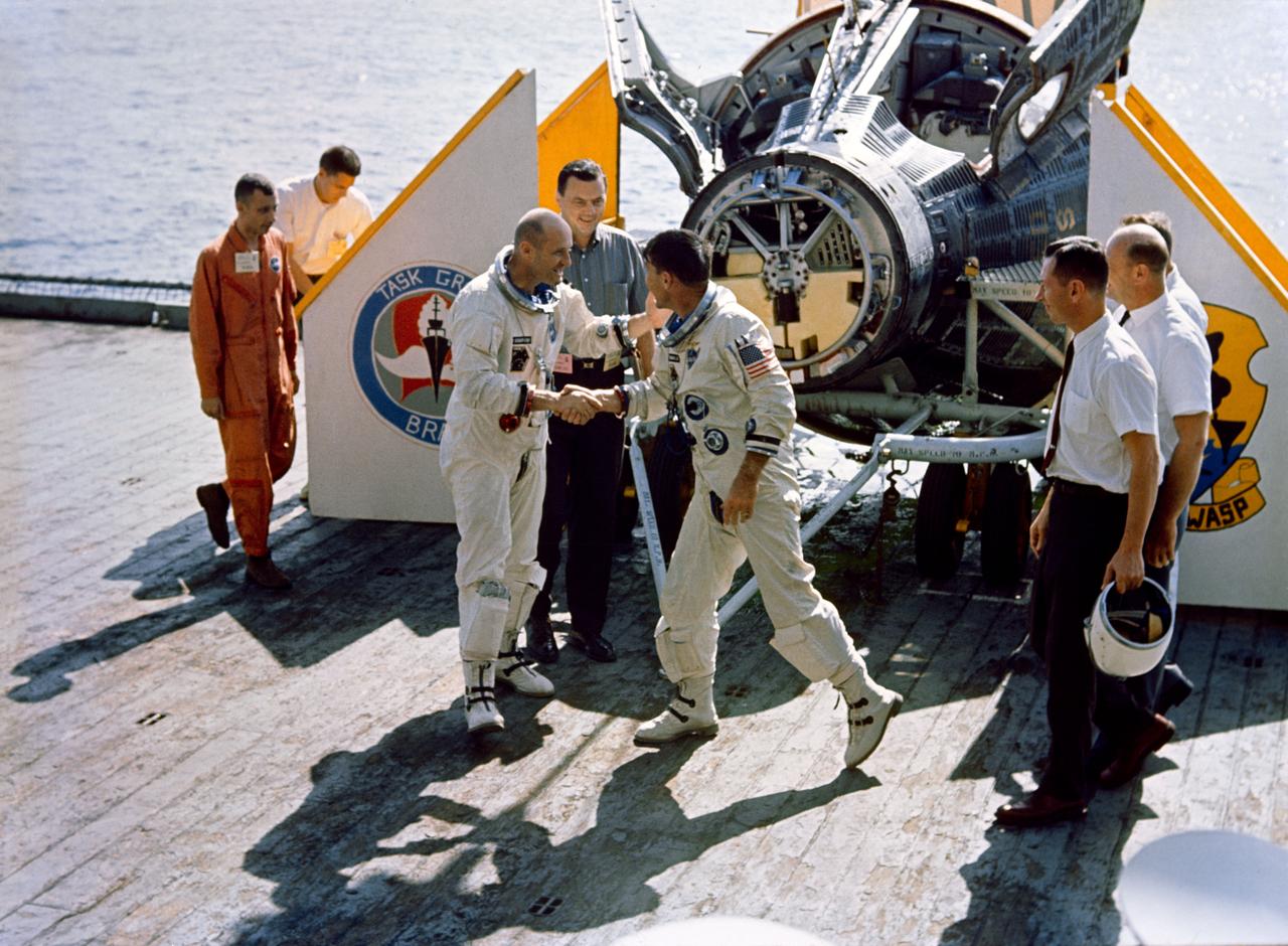 S65-61859 (16 Dec. 1965) --- Astronauts Walter M. Schirra Jr. (right), command pilot, and Thomas P. Stafford, pilot, shake each other's hand as they arrive aboard the aircraft carrier USS Wasp to conclude their 25-hour, 52-minute Gemini-6 spaceflight. Photo credit: NASA or National Aeronautics and Space Administration