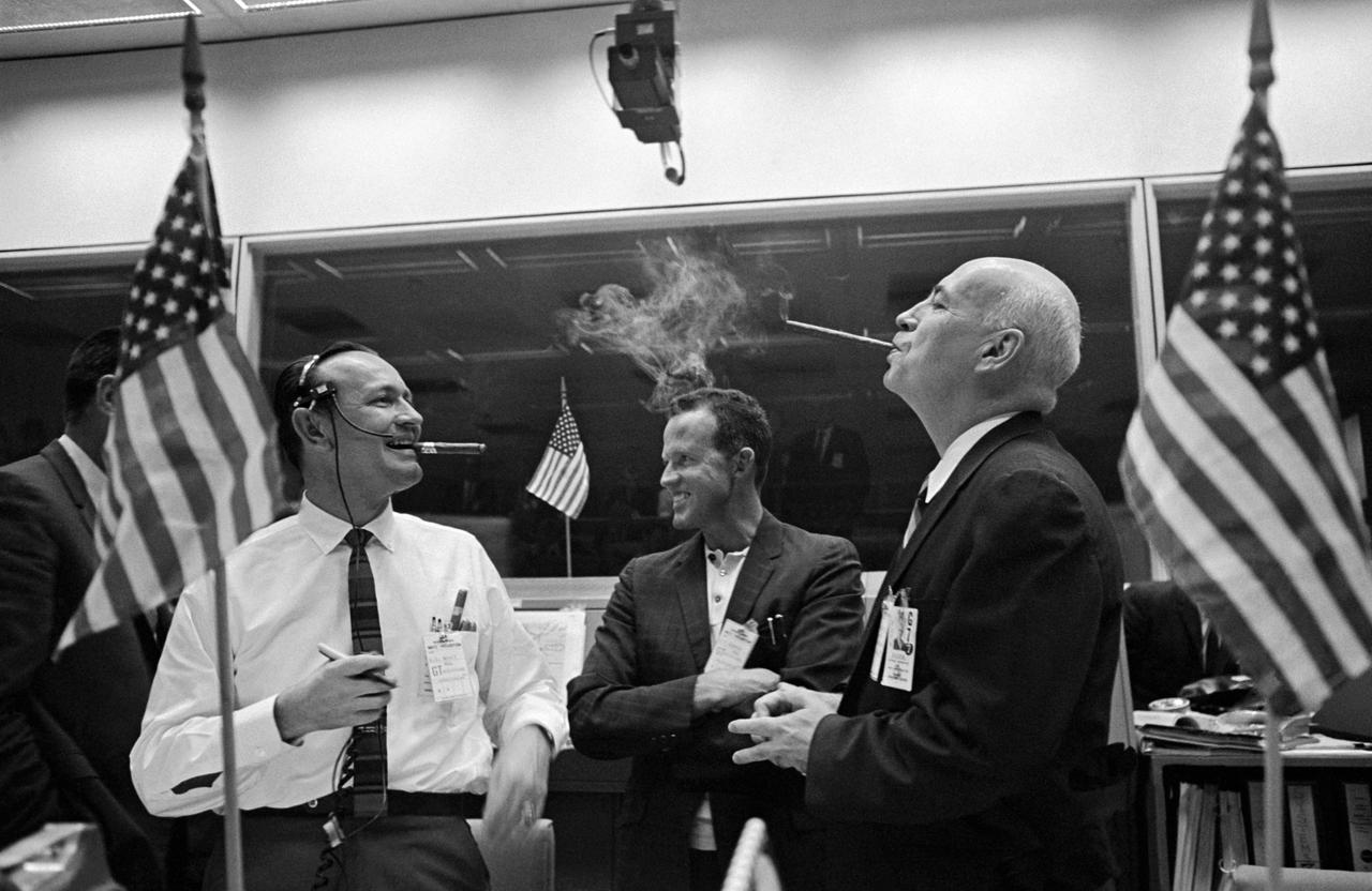 S65-62719 (15 Dec. 1965) --- Discussing the successful and historic rendezvous in space of the National Aeronautics and Space Administration?s Gemini-6 and 7 spacecrafts are, Christopher C. Kraft Jr. (left), red team flight director; astronaut L. Gordon Cooper Jr. (center); and Dr. Robert R. Gilruth, Manned Spacecraft Center director. Consoles in the Center were decorated with small American flags and the traditional cigars were lit to celebrate the rendezvous. Crew members of the two spacecraft are astronaut Walter M. Schirra Jr., command pilot, and Thomas P. Stafford, pilot, Gemini-6; and astronauts Frank Borman, command pilot, and James A. Lovell Jr., pilot, Gemini-7. Photo credit: NASA or National Aeronautics and Space Administration