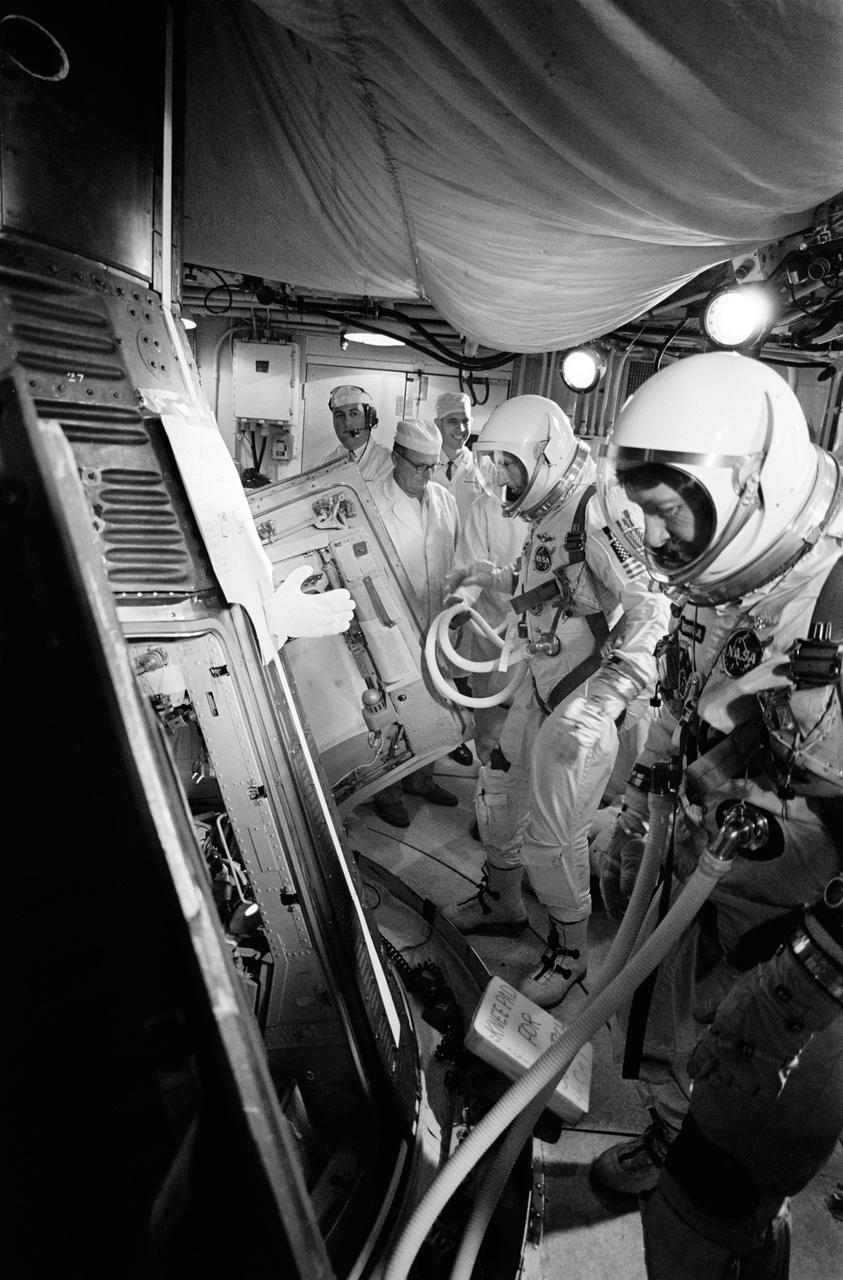 S65-66744 (15 Dec. 1965) --- Insertion of astronauts Walter M. Schirra Jr. (foreground) and Thomas P. Stafford into Gemini-6 spacecraft prior to launch. Photo credit: NASA or National Aeronautics and Space Administration